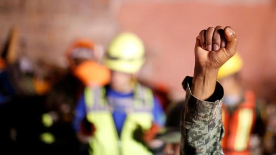 A Mexican soldier gestures to ask for silence as he and his team search for survivors in a collapsed building after an earthquake at Condesa neighborhood in Mexico City